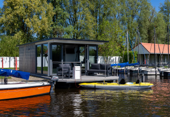 Moderne woonboot bij Marina Heeg in Nederland, omgeven door boten, water en een gezellig terras.