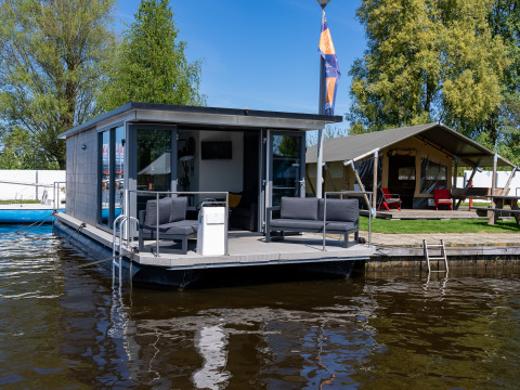 Foto vom Houseboat Heeg in der Marina Heeg, Niederlande, mit Terrasse und Sitzgelegenheiten am Wasser.