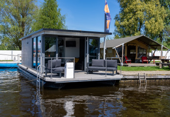 Et foto af Houseboat Heeg ved Marina Heeg i Holland, med terrasse og sofaer ved vandet.