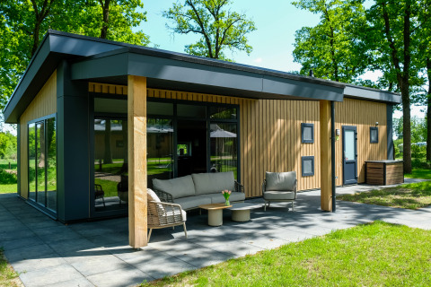 Buitenaanzicht van de Wood Cottage met eigentijdse patio in Holiday park De Witte Berg, Nederland.