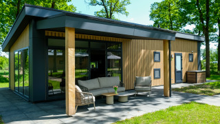 Buitenaanzicht van de Wood Cottage met eigentijdse patio in Holiday park De Witte Berg, Nederland.