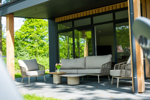 Moderne terras aan Wood Cottage, vakantiepark De Witte Berg, Nederland, met tuinmeubilair.