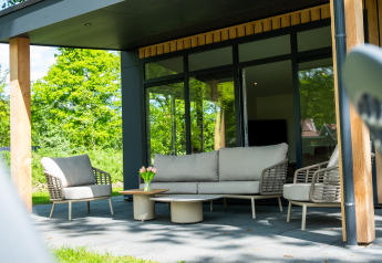 Moderne terras aan Wood Cottage, vakantiepark De Witte Berg, Nederland, met tuinmeubilair.