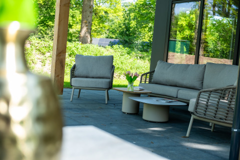 Modern tuinmeubilair met sofa en zetel bij Wood Cottage in vakantiedomein De Witte Berg, Nederland.