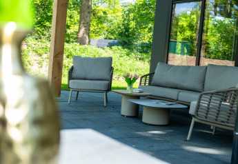 Moderne udendørs siddeområde med sofa, lænestol og bord, set ved Wood Cottage i De Witte Berg, Holland.