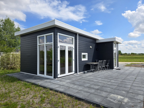 Modernes schwarzes Turfsteker Chalet bei De Tien Heugten in den Niederlanden mit Terrasse und Stühlen.