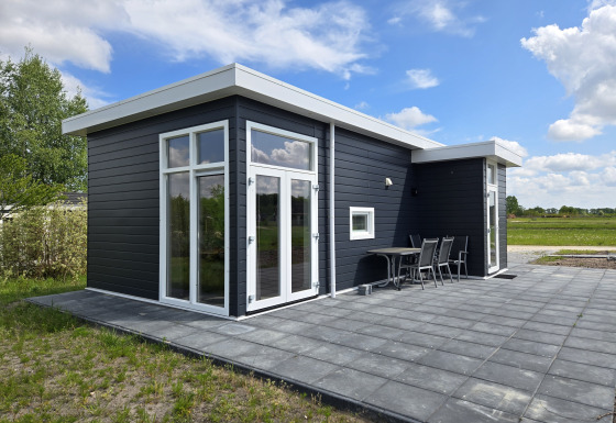 Moderno chalet negro Turfsteker en De Tien Heugten, Países Bajos, con gran terraza y muebles exteriores.