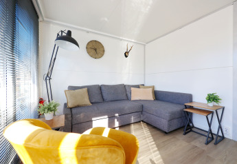 Moderne woonkamer op Houseboat De Hoop bij Marina Parcs, met grijze bank, gele stoel en veel licht.