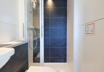 Moderne badeværelse med væghængt toilet og brusekabine på husbåd 'De Hoop' i Nederlandene.