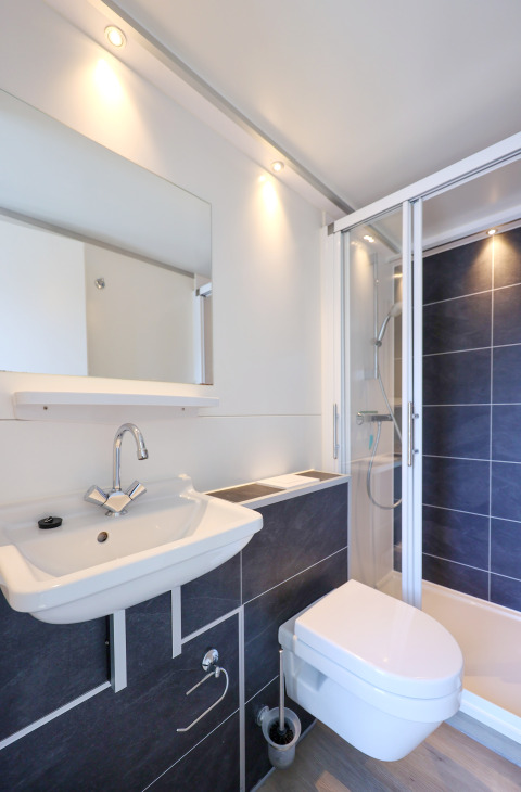 Baño moderno con lavabo, inodoro suspendido y ducha en la casa flotante 'De Hoop' en los Países Bajos.