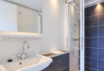 Baño moderno con lavabo, inodoro suspendido y ducha en la casa flotante 'De Hoop' en los Países Bajos.