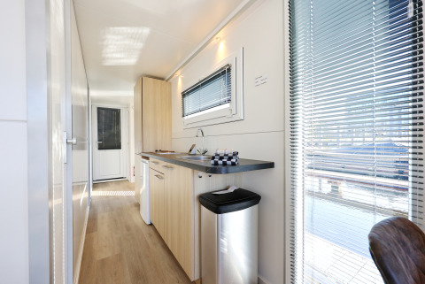 Vista interior de la cocina moderna en la casa flotante 'De Hoop' en Marina Parcs, Países Bajos, con ventanas.