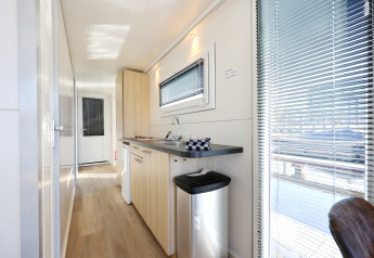 Vista interior de la cocina moderna en la casa flotante 'De Hoop' en Marina Parcs, Países Bajos, con ventanas.