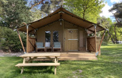 Tienda safari Summer Lodge en Beerze Bulten, Países Bajos, con porche, sillas y mesa de picnic exterior.