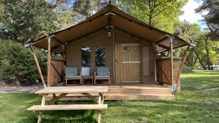 Safari-Zelt Summer Lodge auf Beerze Bulten in den Niederlanden, mit Veranda, Stühlen und Picknicktisch.