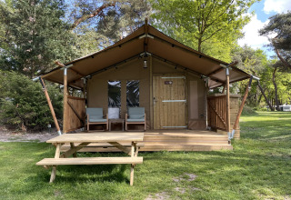 Tienda safari Summer Lodge en Beerze Bulten, Países Bajos, con porche, sillas y mesa de picnic exterior.