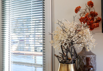 Living area on houseboat De Hoop with vases and table, window blinds, and marina view in the Netherlands.