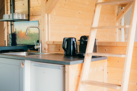 Coin cuisine avec bouilloire, cafetière et échelle dans la cabane Round Holly Tent au parc Sallandshoeve, Pays-Bas.