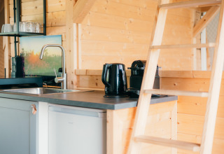 Keukenhoek met waterkoker, koffiemachine en trap in de houten Round Holly Tent bij Sallandshoeve, Nederland.