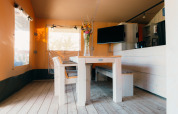 Essbereich mit Holztisch und Bank in einem Safarizelt im Holiday Park Sallandshoeve, Niederlande.
