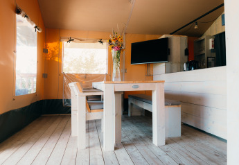 Spiseområde med træbord og bænk i et safari-telt på Holiday Park Sallandshoeve, Holland.