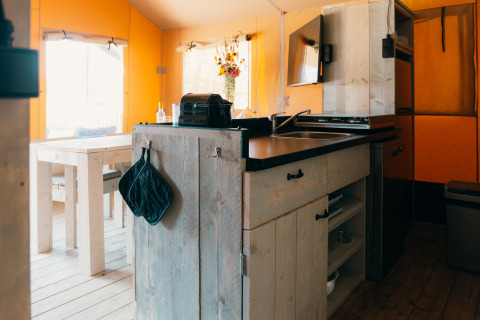 Interior of Safari cottage tent at Holiday Park Sallandshoeve in the Netherlands with kitchen and table.