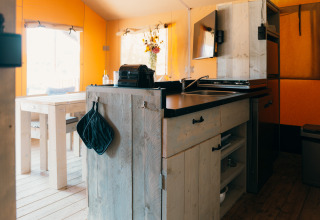 Interior of Safari cottage tent at Holiday Park Sallandshoeve in the Netherlands with kitchen and table.
