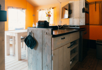 Interior of Safari cottage tent at Holiday Park Sallandshoeve in the Netherlands with kitchen and table.