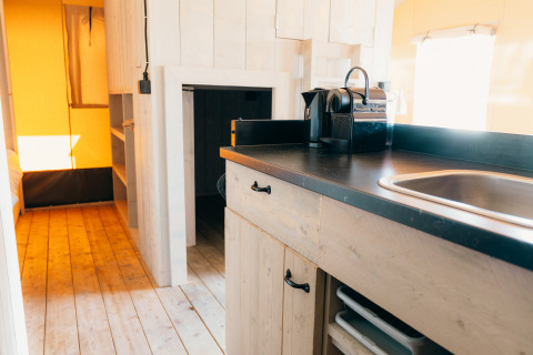 Interieur van een safaritent met houten vloer en kitchenette bij Holiday Park Sallandshoeve, Nederland.