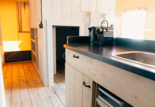 Interior of a safari cottage with wooden floor and kitchenette at Holiday Park Sallandshoeve, Netherlands.