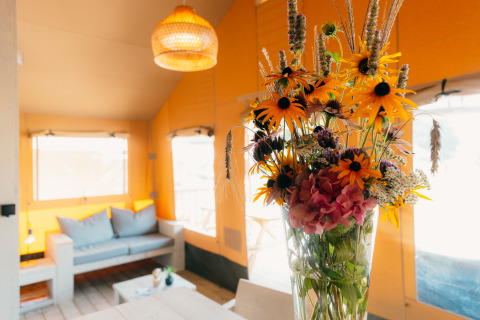 Bouquet of wildflowers in a glass vase inside the bright Safari Cottage tent at Holiday Park Sallandshoeve.