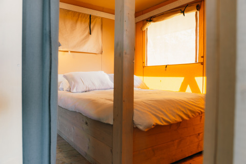Acogedor dormitorio con cama doble en tienda safari, Safari cottage, Holiday Park Sallandshoeve, Países Bajos.