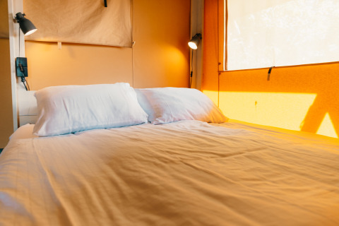 Intérieur d’une tente Safari Cottage au Holiday Park Sallandshoeve avec lit et éclairage naturel chaleureux.
