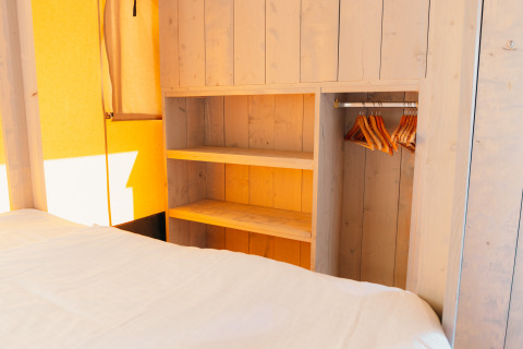 Intérieur de la tente Safari cottage à Holiday Park Sallandshoeve avec penderie en bois et cintres.