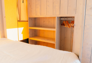 Intérieur de la tente Safari cottage à Holiday Park Sallandshoeve avec penderie en bois et cintres.
