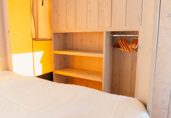 Intérieur de la tente Safari cottage à Holiday Park Sallandshoeve avec penderie en bois et cintres.