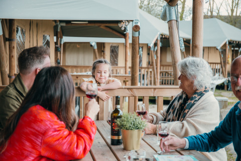 Famille dégustant du vin sur la terrasse d’un cottage safari au Holiday Park Sallandshoeve aux Pays-Bas.
