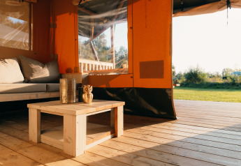 Intérieur de la tente Safari cottage au Holiday Park Sallandshoeve, avec coin salon et vue sur la nature.