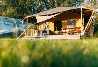 Tienda Safari cottage en Holiday Park Sallandshoeve, Países Bajos, con terraza, sofá y mesa de picnic.