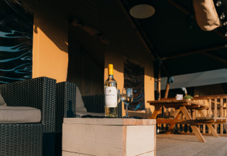 Weinflasche und Glas auf Tisch vor Safari-Zelt Safari Cottage im Ferienpark Sallandshoeve, Niederlande.