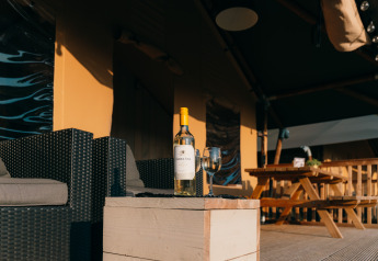 Bottiglia di vino e bicchiere su tavolo davanti alla tenda Safari Cottage a Holiday Park Sallandshoeve, Olanda.