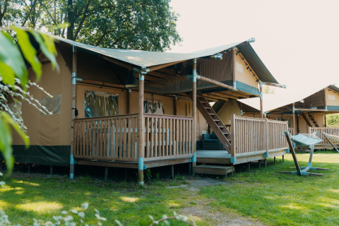 Tienda safari llamada Ranger Lodge con terraza de madera en Holiday Park Sallandshoeve, Países Bajos.