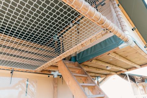 Interno di una tenda safari con scala in legno e rete al Holiday Park Sallandshoeve, Paesi Bassi.