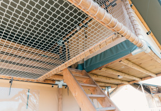 Interno di una tenda safari con scala in legno e rete al Holiday Park Sallandshoeve, Paesi Bassi.
