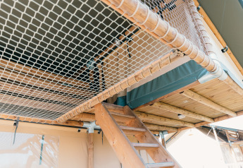 Interieur van een safaritent met houten trap en net bij Holiday Park Sallandshoeve, Nederland.