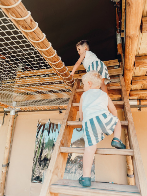 Dos niños suben por una escalera dentro de una tienda safari en Ranger Lodge, Holiday Park Sallandshoeve, Países Bajos.