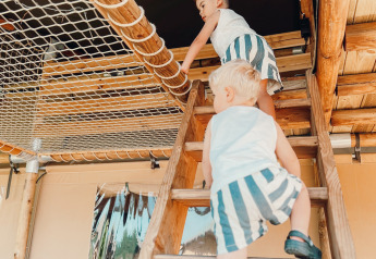 Two children climb stairs inside a safari tent at Ranger Lodge, Holiday Park Sallandshoeve, Netherlands.