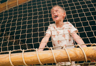 Bambino che gioca su una rete di corde nella tenda safari Ranger Lodge all’Holiday Park Sallandshoeve, Paesi Bassi.