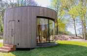 Tiny house ronde Lumni Pod avec grande baie vitrée à Wilsumer Berge, Allemagne, entourée d'arbres.