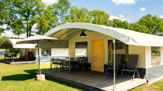 Safaritent Tentvilla op recreatiepark De Witte Berg in Nederland met terras, stoelen en parasol.